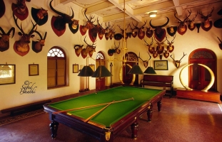 This is a magnificent image of a billiard-room in  Korea state swaged in silence and surrounded by trophies, the ponderous table unsheeted, it seems to be the hushed room of a palace