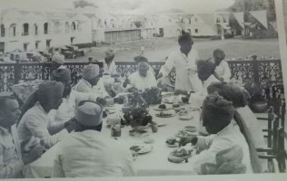 Photoghrap of Rewa cheifs taking breakfast in front of Rewah fort Palace where front view of fort palace has been capture with Maharaj saheb some car collection also be seen in Picture. (Rewah)